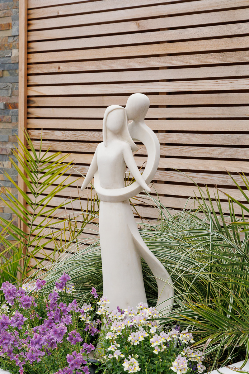 Close-up detail of modern garden sculpture against with soft planting.