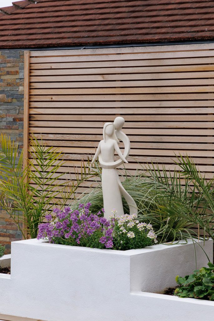 Garden sculpture with cedar cladding backdrop and architectural planting.
